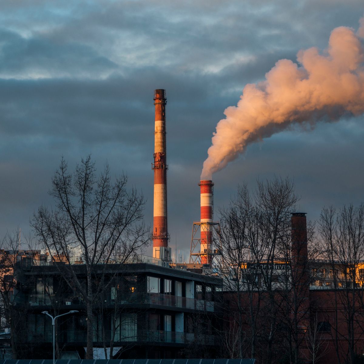 Industriskorstenar som släpper ut rök mot en skymningshimmel